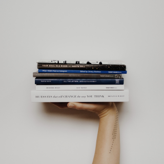 someone is holding a stack of books