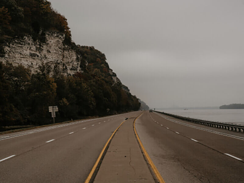 highway road next to sea and mountain