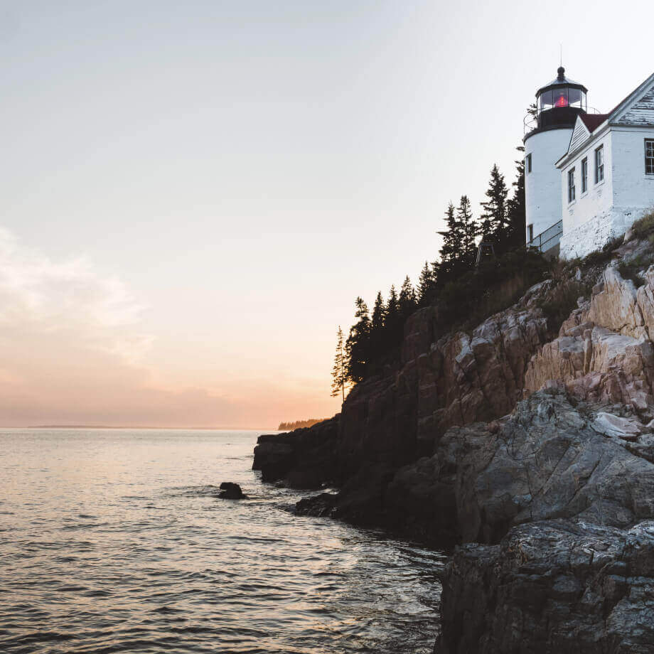 lighthouse sitting on the rocks next to sea